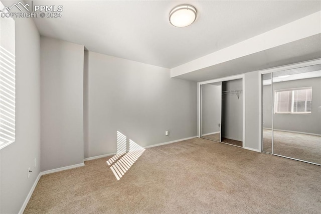 unfurnished bedroom with light carpet and two closets