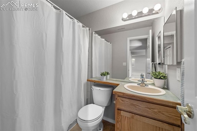 bathroom featuring curtained shower, vanity, and toilet