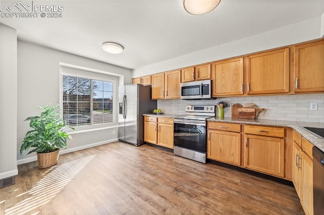 kitchen featuring wood-type flooring, appliances with stainless steel finishes, and tasteful backsplash