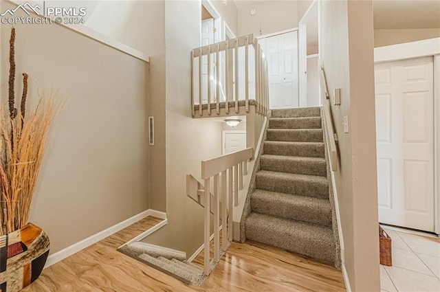 stairway with vaulted ceiling and hardwood / wood-style flooring