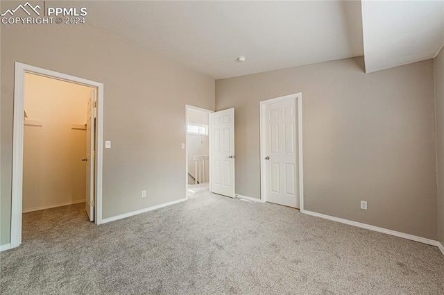 unfurnished bedroom featuring a spacious closet, a closet, and carpet