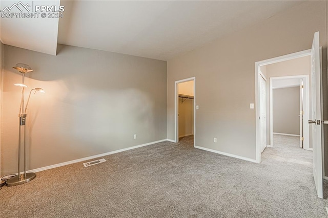 unfurnished bedroom with a closet, a walk in closet, and carpet floors