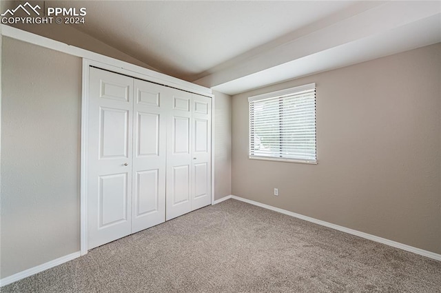 unfurnished bedroom with carpet, vaulted ceiling, and a closet