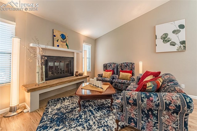 living room with a healthy amount of sunlight, wood-type flooring, and vaulted ceiling