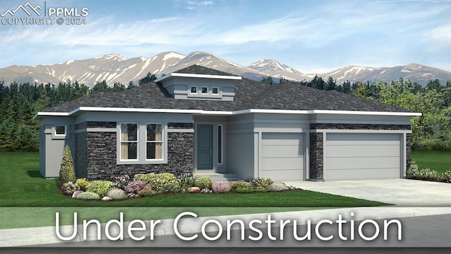 prairie-style house with a front yard, an attached garage, concrete driveway, stone siding, and a mountain view