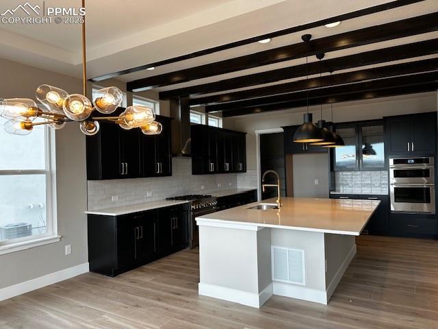 kitchen featuring visible vents, a sink, stainless steel appliances, light countertops, and dark cabinets