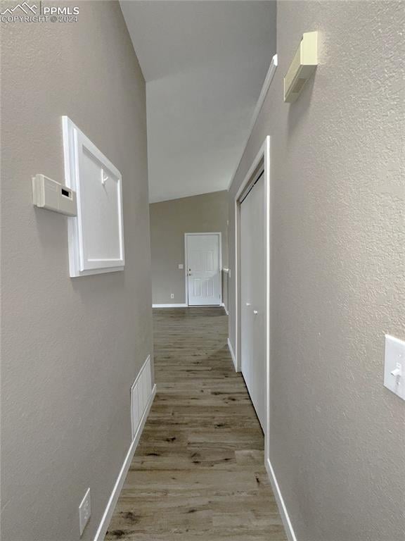 hall with wood-type flooring and lofted ceiling