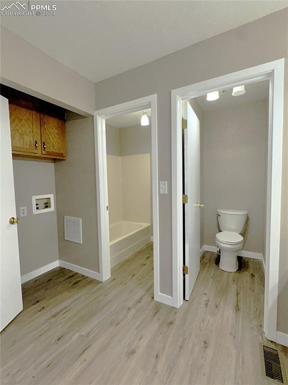 bathroom featuring toilet, hardwood / wood-style flooring, and a washtub