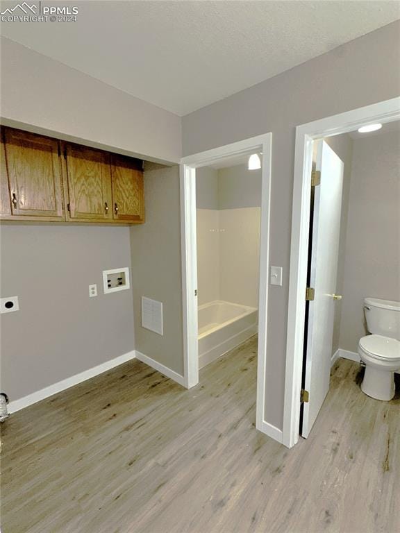 laundry area with light hardwood / wood-style flooring, washer hookup, hookup for an electric dryer, and cabinets