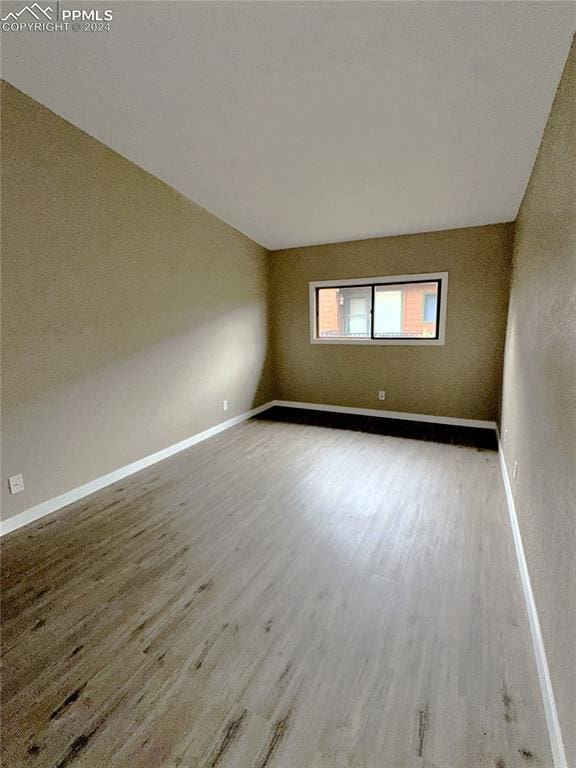 unfurnished room with lofted ceiling and hardwood / wood-style flooring