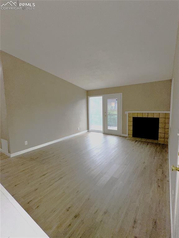 unfurnished living room with a brick fireplace and light wood-type flooring