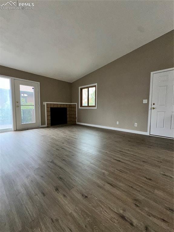 unfurnished living room featuring a tiled fireplace, lofted ceiling, and dark hardwood / wood-style floors