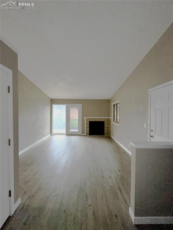 unfurnished living room featuring lofted ceiling, carpet, and a tiled fireplace