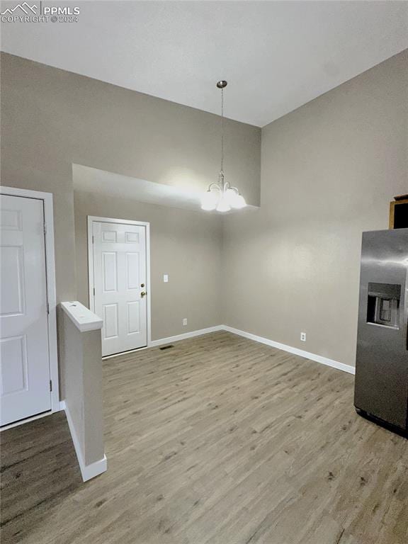 unfurnished dining area featuring light hardwood / wood-style floors and an inviting chandelier