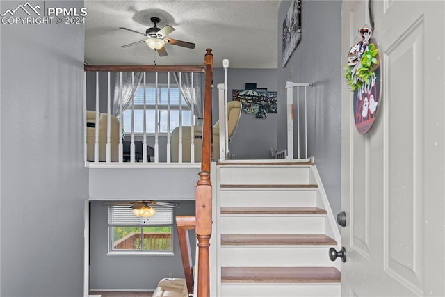 stairway with ceiling fan and a textured ceiling