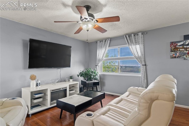 living room with a textured ceiling, dark wood-type flooring, and ceiling fan