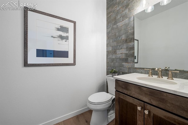 bathroom featuring toilet, hardwood / wood-style floors, vanity, and tile walls