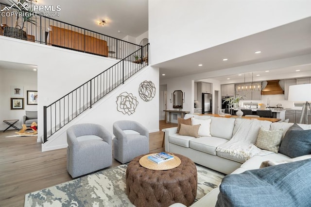 living room featuring a high ceiling, light hardwood / wood-style flooring, and an inviting chandelier