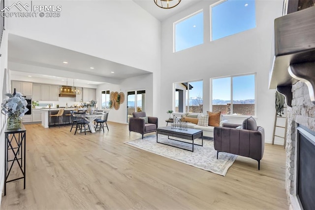 8542 Noreen Falls Dr, Colorado Springs, CO 80924 - living area featuring light wood finished floors, a mountain view, a stone fireplace, a towering ceiling, and recessed lighting