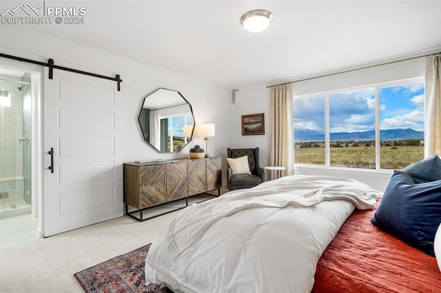 bedroom with a barn door, a mountain view, carpet floors, and ensuite bath