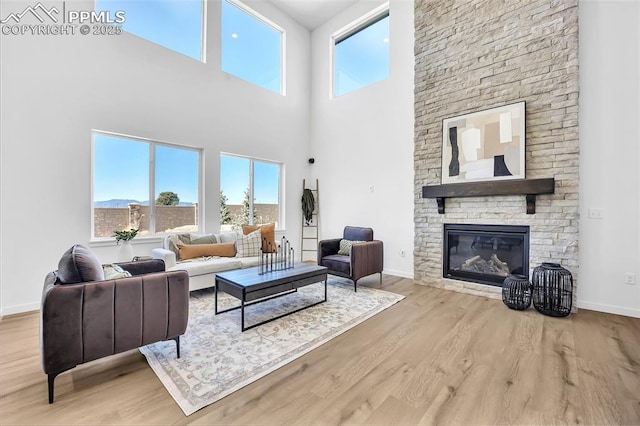 8542 Noreen Falls Dr, Colorado Springs, CO 80924 - living room featuring wood finished floors, plenty of natural light, a stone fireplace, baseboards, and a towering ceiling