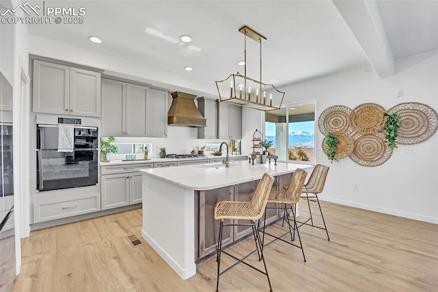 8542 Noreen Falls Dr, Colorado Springs, CO 80924 - kitchen with a sink, custom exhaust hood, light wood-style floors, light countertops, and a chandelier