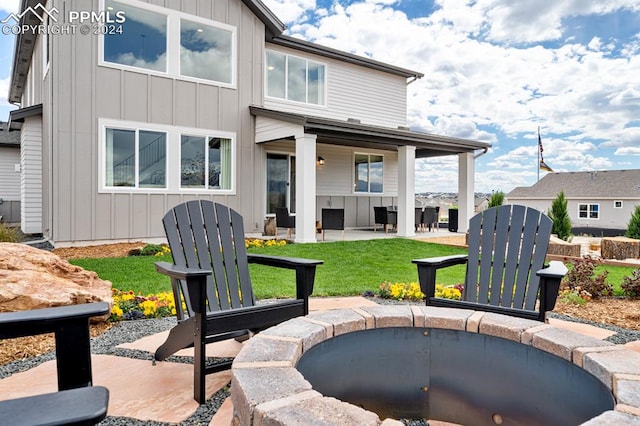 back of property with a patio area, a fire pit, and a yard