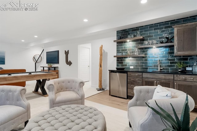 interior space with stainless steel fridge, decorative backsplash, dark brown cabinetry, and light hardwood / wood-style floors