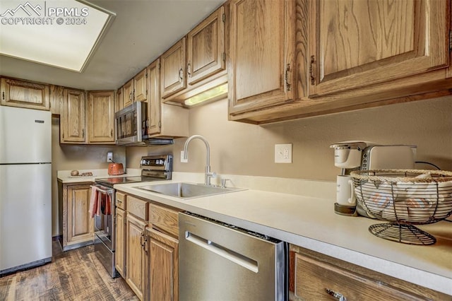 kitchen with dark hardwood / wood-style floors, stainless steel appliances, and sink