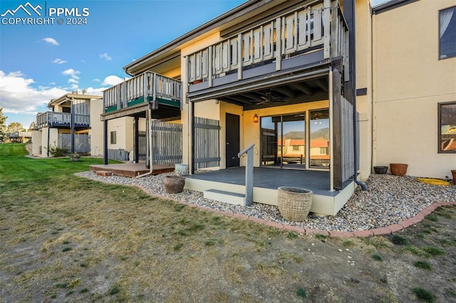 rear view of house with a balcony, a patio, and a lawn