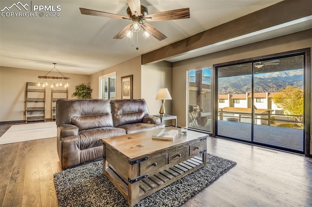 living room with beam ceiling, wood-type flooring, and ceiling fan with notable chandelier