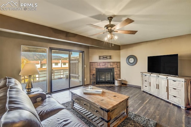 living room featuring ceiling fan, a tile fireplace, and dark hardwood / wood-style floors