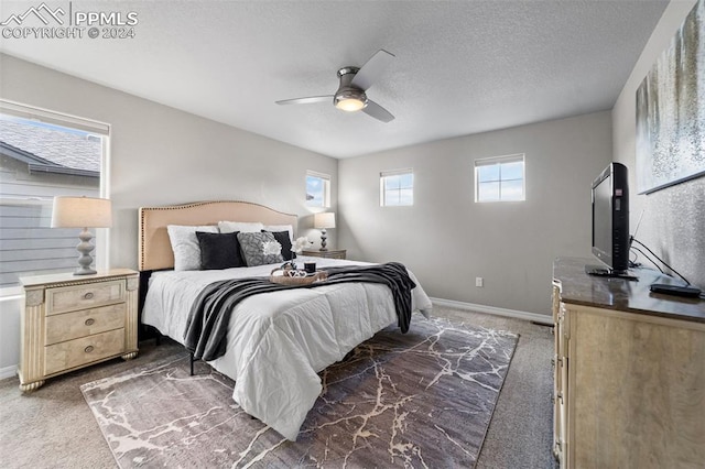 bedroom with ceiling fan, a textured ceiling, and dark colored carpet