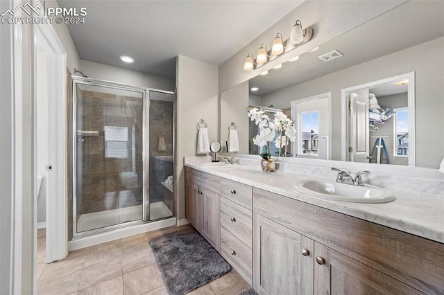 bathroom with vanity, a shower with shower door, and tile patterned floors