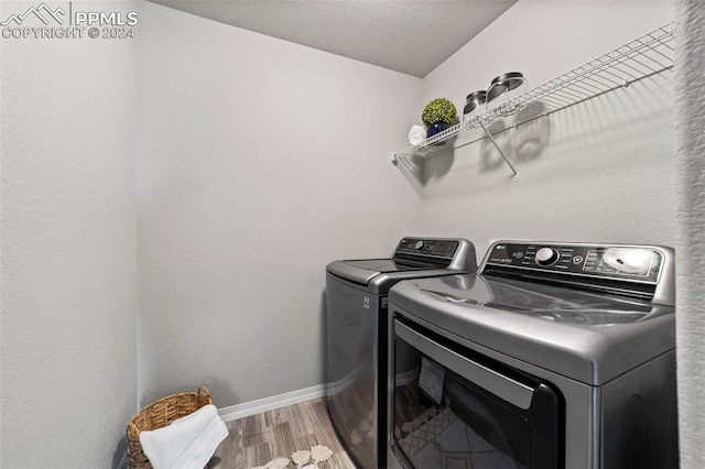 laundry room with a textured ceiling, washing machine and clothes dryer, and hardwood / wood-style floors