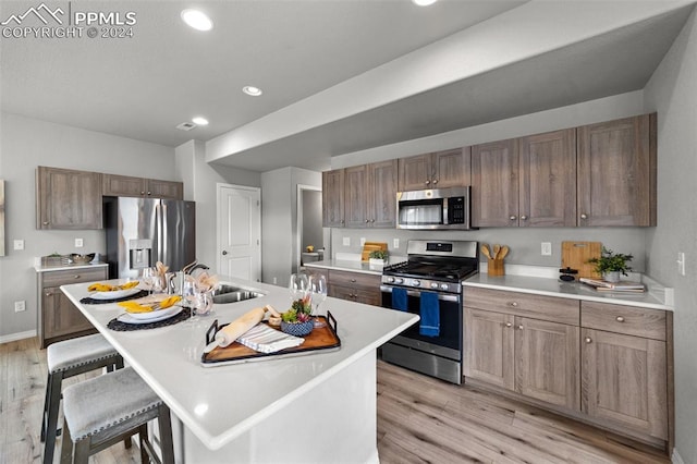 kitchen featuring light hardwood / wood-style floors, a breakfast bar, stainless steel appliances, and a center island with sink