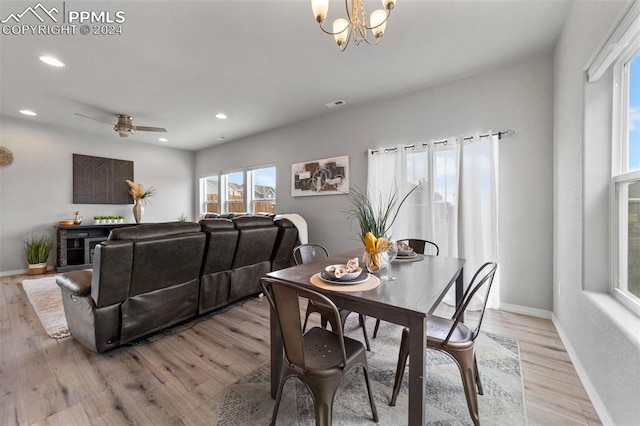 dining area with ceiling fan with notable chandelier and light wood-type flooring