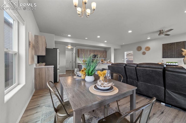 dining space with ceiling fan with notable chandelier and light hardwood / wood-style floors