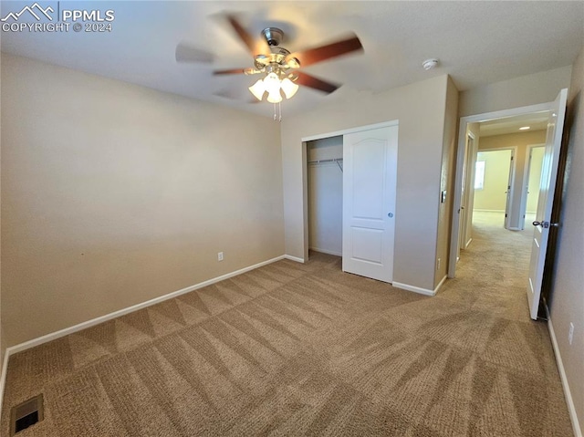 unfurnished bedroom featuring a closet, light colored carpet, and ceiling fan