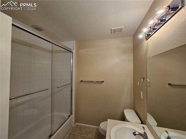 full bathroom with toilet, a textured ceiling, bath / shower combo with glass door, and tile patterned flooring