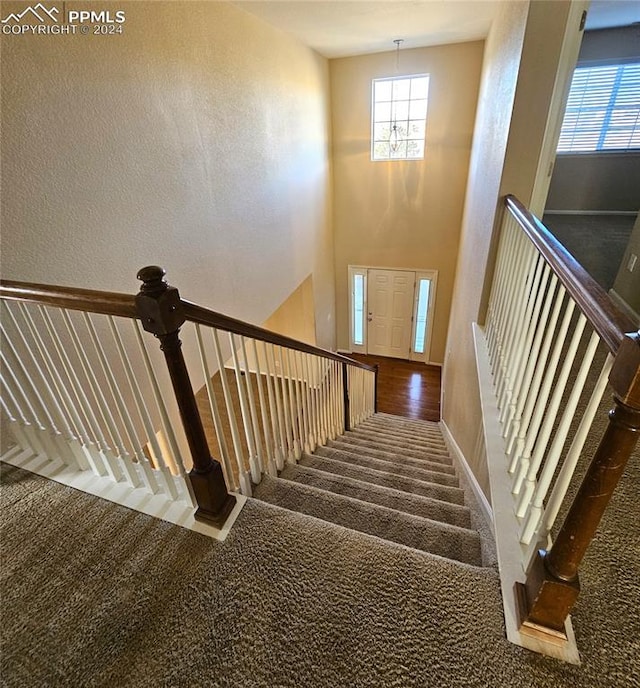 staircase with carpet flooring and a chandelier