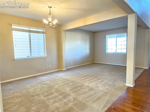 unfurnished room with wood-type flooring and a chandelier