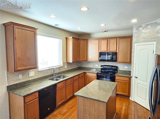 kitchen featuring sink, light hardwood / wood-style floors, black appliances, and a center island