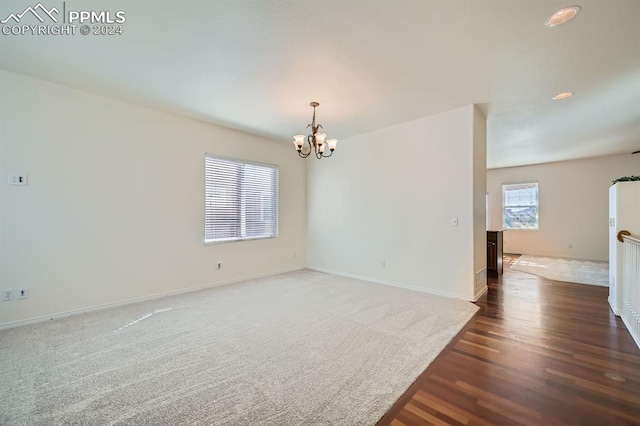 empty room featuring dark wood-type flooring and a notable chandelier