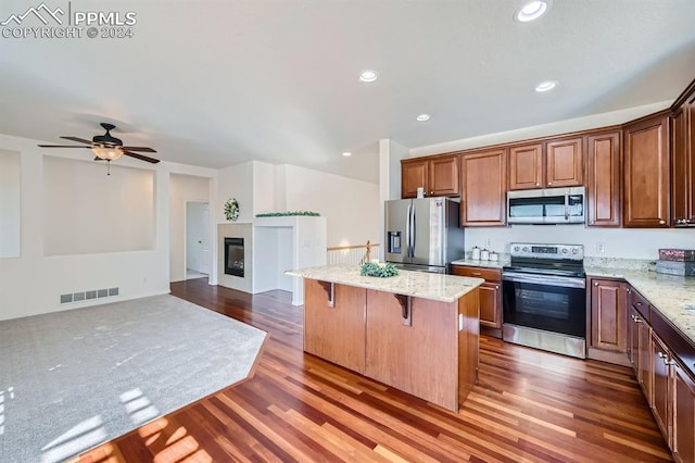 kitchen with a kitchen breakfast bar, dark hardwood / wood-style flooring, a kitchen island, and appliances with stainless steel finishes