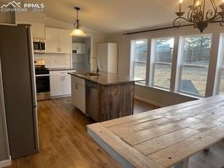 kitchen featuring a center island with sink, decorative light fixtures, white cabinetry, and appliances with stainless steel finishes