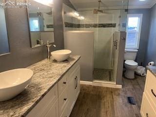 bathroom with wood-type flooring, an enclosed shower, toilet, vanity, and ornamental molding