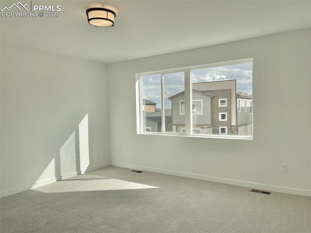 carpeted spare room featuring baseboards and visible vents