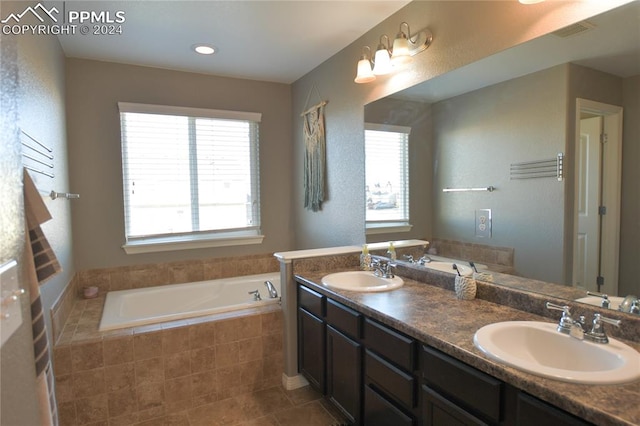 bathroom featuring vanity, a relaxing tiled tub, and tile patterned flooring