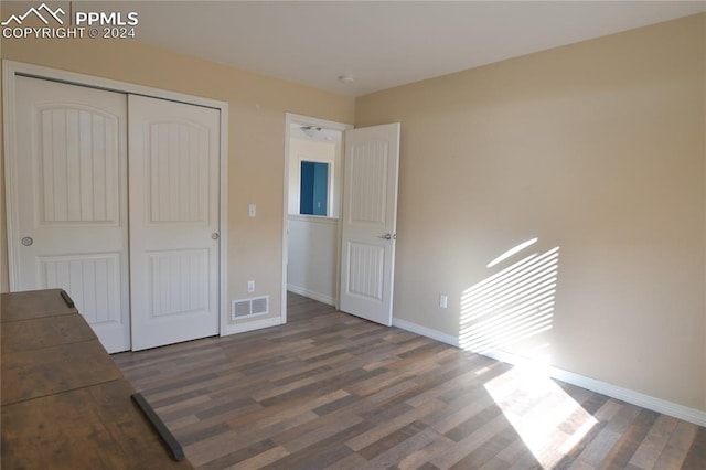 unfurnished bedroom featuring a closet and dark hardwood / wood-style flooring